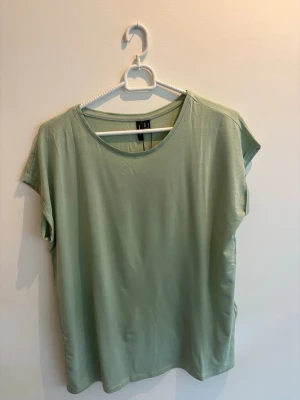 Ljusgrön basic t-shirt - En enkel och stilren ljusgrön t-shirt med rund hals och korta ärmar. T-shirten har en avslappnad passform och är tillverkad i mjukt bomullsmaterial. 