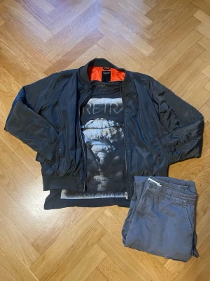 Klädpaket – Lager 157 & Firetrap - Säljer hela den här outfiten som ett paket. Allt är i fint skick.   Svart bomberjacka (Lager 157): Med orange foder på insidan. Storlek L   Mörkgrå t-shirt (Firetrap): Med tryck på bröstet.  Storlek XL   Gråa byxor (Lager 157) storlek L.                     Tveka inte att fråga något. Obs! Inga förhandlingar 