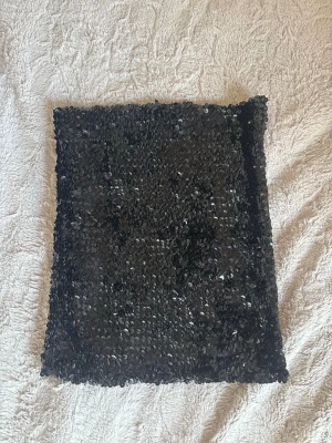 Svart paljett tubtopp Gina Tricot - Säljer en svart tubtopp från Gina Tricot i storlek XS. Toppen är täckt med glittriga paljetter som ger en riktigt snygg look. Perfekt för dig som vill sticka ut och glänsa lite extra.