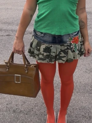 Y2K camo mini skirt med jeansdetalj 🌺 - Unik Y2K-minikjol med camouflageprint, jeansmidja och vacker blomapplikation. En riktig statement-kjol som passar perfekt till haltertop, baby tee eller boots. Märkt storlek 38. Bra skick! 🌺✨