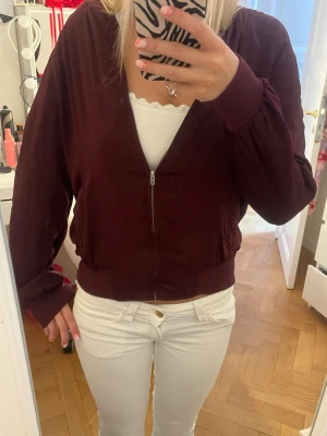 Vinröd bomberjacka med dragkedja - Snygg vinröd bomberjacka med dragkedja framtill! Fråga gärna om mer bilder om ni vill ha!
