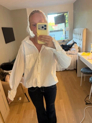 Vit oversized skjorta med knappar - Säljer en vit oversized skjorta i bomull med klassisk krage och knäppning framtill. Skjortan har långa ärmar och två bröstfickor, perfekt för en avslappnad och trendig look. Passar till jeans eller kjol för en enkel stil.den har en liten fläk som jag inte har provat om den gör bort