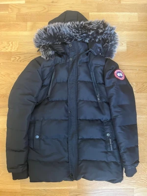 Canada Goose vinterjacka svart, storlek S - Säljer en Canada Goose vinterjacka i svart, storlek S. Jackan är i bra begagnat skick och är varm och bekväm.  Observera att en dragkedja saknas, vilket syns på bilderna och är trasigt under armhålan i högersidan. I övrigt är jackan i fint skick.