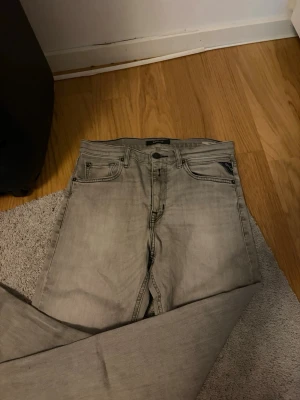 Grå jeans från Replay - Säljer ett par snygga grå jeans från Replay. Klassisk femficksmodell med dragkedja och knapp i midjan. Jeansen har en tvättad look och raka ben. Perfekta till en avslappnad stil och passar till det mesta.