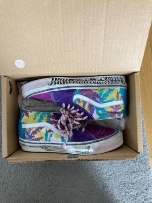 Färgglada mönstrade vans - Unika sneakers med lila, blå, gul och vit färg i ett grafiskt mönster. Skorna har rosa skosnören med svarta prickar och vit sula med svart dekor. Klassisk siluett med mellanhögt skaft och vit sidostripes. Perfekta för dig som vill sticka ut.