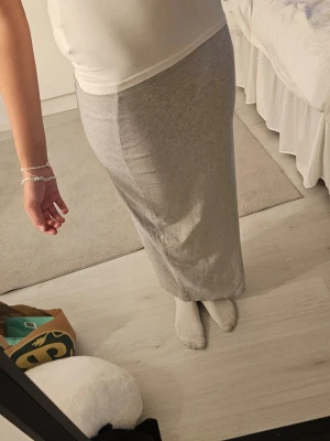 Ljusgrå lång tight kjol - Säljer en ljusgrå, lång och tight kjol i mjukt stretchigt material. Kjolen har en rak passform och sitter högt i midjan, perfekt för en clean och enkel look. Passar till både sneakers och boots.man kan även vika upp den hur man vill ha den, om ni tittar på siata bilden så e d fett snyggt den är från tpkyo