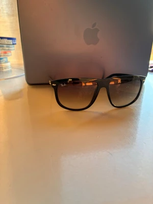 Svarta Ray-Ban solglasögon - Snygga svarta solglasögon från Ray-Ban med klassisk wayfarer-form. Bågarna är svarta och glasen har en mörk toning som ger en cool look. Perfekta för soliga dagar och ger en tidlös vibe till din outfit.