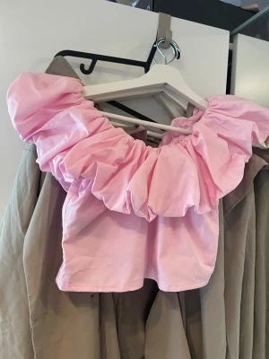 Volang topp - En ny supersöt  rosa croppad topp med stora puffiga volangdetaljer runt hela ringningen. (Oanvänd) 