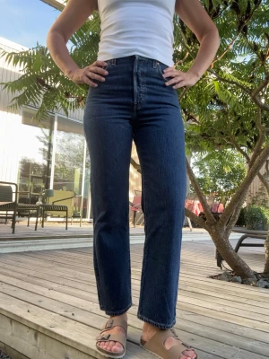 Levi’s ribcage Mörkblå raka jeans med hög midja - Snygga mörkblå jeans med hög midja och raka ben. Klassisk femficksmodell med gul söm och normal längd. Jeansen har en tidlös look och passar perfekt till en enkel topp eller hoodie. Materialet är kraftig denim i bomull. Använda bara en gång, som nya. 