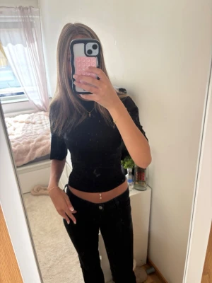 Svart croppad topp med halvlånga ärmar - Säljer en svart croppad topp med halvlånga ärmar och tight passform. Toppen har en enkel och stilren design som passar perfekt till jeans eller kjol.
