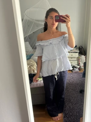 Ljusblå offshoulder volangblus - Säljer en ljusblå blus med offshoulder och volangdetaljer. Toppen har en lös passform och resår vid axlarna. Verkligen så snygg🩵🩵