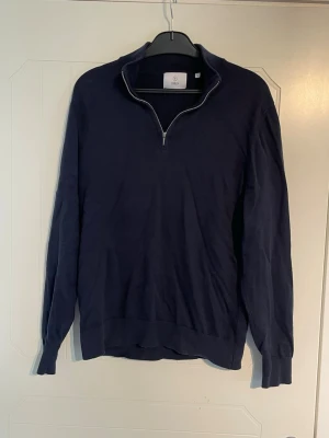 Mörkblå halvzip från Bläck - Mörkblå långärmad tröja med halv dragkedja från Bläck. Tröjan har en hög krage och ribbade muddar vid ärmslut och nederkant. Perfekt för lager på lager och enkel att matcha med olika outfits. Mycket bra skick (använd ett fåtal gånger), ser bara lite skrynklig ut på bild!