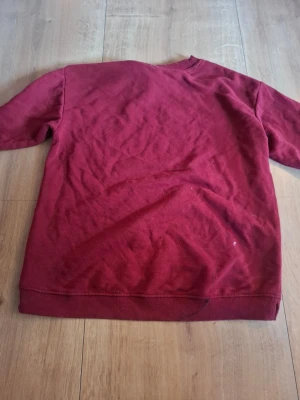 Vinröd sweatshirt från H&M - En enkel och snygg vinröd sweatshirt från H&M. Tröjan har rund halsringning, ribbade muddar vid ärmslut och nederkant. Tillverkad i mjukt material som är skönt att ha på sig. Perfekt för en avslappnad och stilren look.