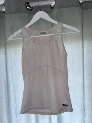 Ljusbeige linnetopp från MyWear - Säljer en enkel och stilren ljusbeige linnetopp från MyWear i storlek M. Toppen har rund halsringning och är ärmlös, perfekt för varma dagar eller som lager under en skjorta. Materialet känns mjukt och lätt mot huden.
