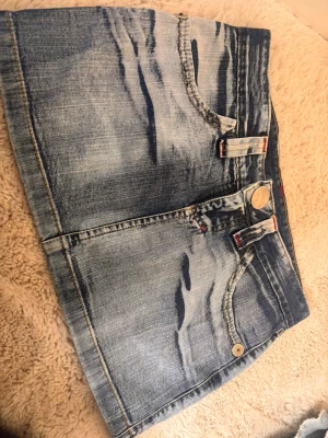 Vintage jeanskjol  - Snygg vintage mini jeanskjol i ljusblå denim med slitna detaljer och röda sömmar. Aldrig använd och köptes på en marknad i Rio de Janeiro för en vecka sen.