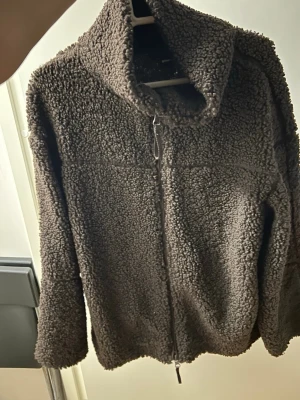 Brun teddyjacka från Gina Tricot - Mysig brun teddyjacka från Gina Tricot i storlek XS. Jackan har hög krage, dragkedja framtill och är gjord i fluffigt teddy-material som håller dig varm. Perfekt för kyliga dagar och enkel att matcha med olika outfits.