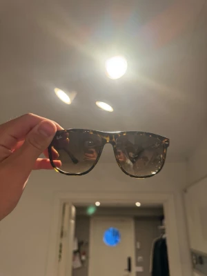 Ray-Ban solglasögon brunmelerade - Säljer ett par Ray-Ban solglasögon med brunmelerad båge och mörka glas. Klassisk och modell med breda skalmar och Ray-Ban-logga på linsen. Mycket bra skick använda men syns inte ens, har tyvärr inte kvar alla orginalförpackningar då de slängdes för ett par år sen, hör av dig om du är intresserad:)