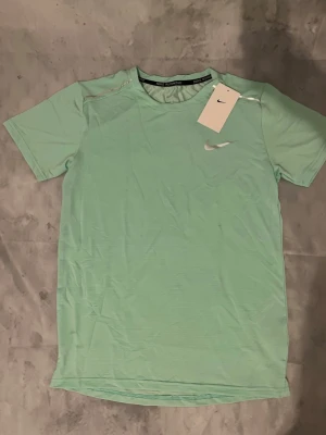 Mintgrönt träningsset från Nike - Säljer ett fräscht mintgrönt träningsset från Nike med t-shirt och shorts. Båda plaggen har Nike-logga i vitt och är gjorda i ett lätt och snabbtorkande material som passar perfekt för träning eller sportaktiviteter.