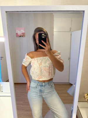 H&m Blommig offshoulder blus - Söt blommig offshoulder blus i ljusa pastellfärger med puffärmar och croppad passform. Blusen har elastiska detaljer vid ärmslut och midja för en bekväm och trendig look. Perfekt för vår och sommar!