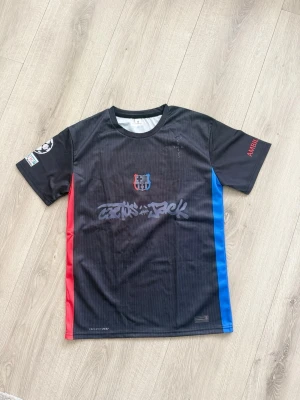 Svart Barcelona fotbollströja - Säljer en svart Barcelona fotbollströja med röda och blå detaljer på sidorna. Good quality och kommer med sin påse