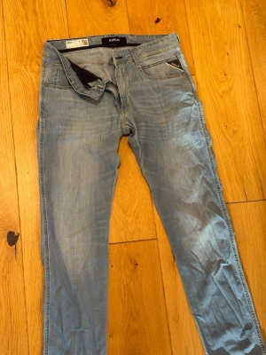 Ljusblå slim fit jeans Replay - Säljer ett par ljusblå slim fit jeans från Replay, modell Anbass. Jeansen har klassisk femficksdesign, dragkedjegylf och snygga slitningar för en avslappnad look. Perfekta till vardagsstilen och lätta att matcha med olika plagg.