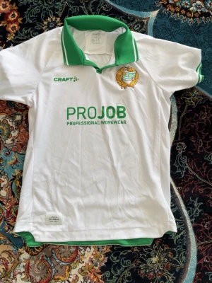Vit Hammarby fotbollströja Craft - Säljer en vit Hammarby fotbollströja från Craft med gröna detaljer och klubbmärke på bröstet. Tröjan har grön krage. Supporter tröja