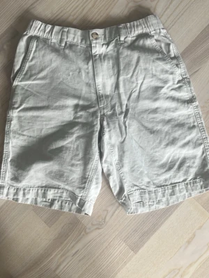 Beiga shorts från Uniqlo i bomull - Snygga beiga shorts från Uniqlo i mjuk bomullsmix. Klassisk modell med normal passform, bälteshällor och fickor fram. Perfekta för varma dagar och enkel att matcha med olika stilar.
