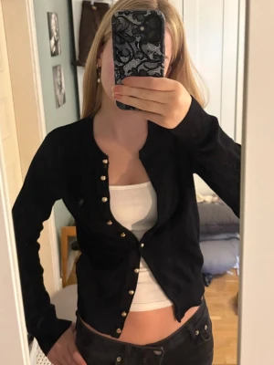 Svart kofta från H&M - Säljer denna stickade svarta koftan med guldknappar! Använd flera gånger men inga synliga defekter, smått nopprig på vissa ställen. Säljer då den inte kommer till användning. Passar perfekt till hösten! Storlek XS