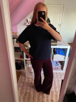 Mörkblå stickad t-shirt - Mörkblå stickad t-shirt med korta ärmar och rund hals. Tröjan har en enkel, rak passform och är gjord i ett mjukt, lite luddigt material som ger en avslappnad look. Perfekt att styla med jeans eller kjol för en trendig vardagsoutfit.
