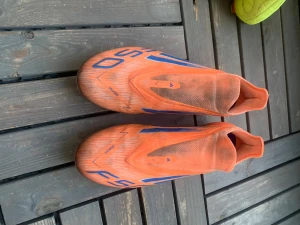 Adidas F50 Elite LL FG orange - Säljer ett par Adidas F50 Elite LL FG fotbollsskor i orange med blå detaljer och vita sulor. Skorna har låg vikt, strömlinjeformad design och är tillverkade i syntetmaterial för bästa prestanda på fasta underlag. Medföljer matchande orange påse.