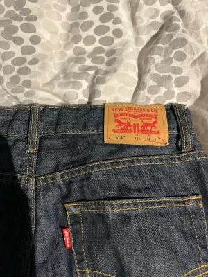 Levi's 514 mörkblå jeans - Säljer ett par klassiska Levi's 514 jeans i mörkblå denim med raka ben och snygga kontrastsömmar. Står W32 men sitter som W27