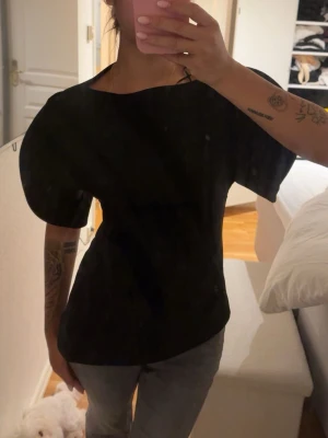 Svart topp med puffärm - Säljer en svart topp med markerade puffärmar och rund halsringning. Toppen har en enkel, stilren design och är lätt att matcha till olika outfits. Perfekt för dig som gillar en trendig och clean look.