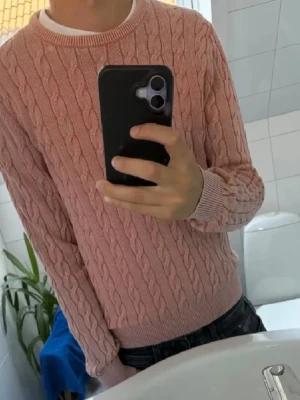 Morris tröja - Säljer en snygg rosa kabelstickad tröja från morris med rund hals och ribbade muddar. Tröjan har ett klassiskt flätmönster och är perfekt för dig som gillar en stilren och trendig look. Passar till jeans eller kjol för en avslappnad outfit.