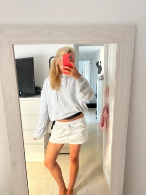 Grå hoodie med paljettvingar - Säljer en ljusgrå hoodie. På ryggen finns stora, glittriga paljettvingar, lite ”tajtare” längst ner i midjan så man lättare kan vika upp den så som på första bilden om man vill. 