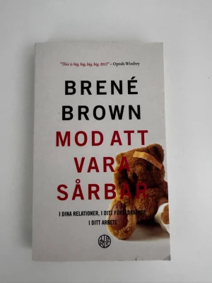 Mod att vara sårbar av Brené Brown - En inspirerande bok av Brené Brown med vit framsida, svart och röd text samt en nalle på omslaget. Boken utforskar sårbarhet i relationer, föräldraskap och arbete. Perfekt för dig som vill utvecklas personligt och förstå styrkan i att vara öppen.