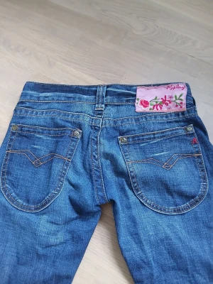 Blå raka jeans med slitningar - Säljer ett par blå jeans med raka ben och snygga slitningar framtill. Jeansen har klassisk femficksmodell, normal midja och detaljerade sömmar. Perfekta för en avslappnad och trendig look. W:25 L:30, säljer då dem inte passar längre, använd ett fåtal ggr.