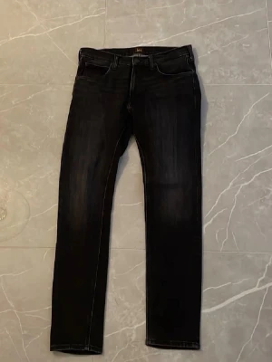 Svarta skinny jeans med stretch - Säljer ett par svarta skinny jeans med lätt tvättade detaljer och smal passform. Jeansen har klassisk femficksdesign, normal midja och är tillverkade i ett stretchigt material för extra komfort. Perfekta för en trendig och avslappnad look.