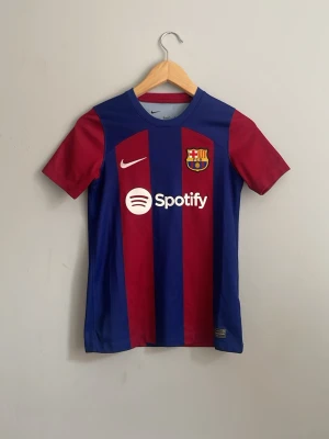 FC Barcelona matchtröja Nike - Säljer en FC Barcelona matchtröja från Nike med klassiska röda och blåa ränder på. Jag har har haft på mig tröjan typ 10 gånger men den har blivit för liten för mig. Den har tyvärr inget namn på ryggen och den är storlek 137-147. Den är perfekt för träningar eller streetwair. Visca Barça y Visca Cataluña🇪🇸❤️💙