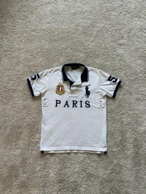 Vit och Svart Paris Big Pony Ralph Lauren Polo Piké Storlek M  - Mycket fin piké i vit färg. | Jeansen är i mycket bra skick och sparsamt använda. |  Äkta som allt annat jag säljer! ✅ |  Storlek: M | Skick: Mycket Bra Skick | Färg: VIT | Märke: RL | Modell: piké |   Hör gärna av dig vid frågor så svarar jag så fort jag kan! 😁 |  (SKU - 235)