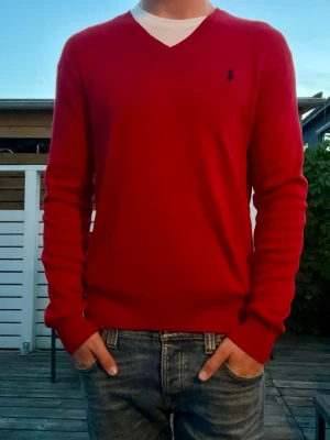 Polo Ralph lauren stickad tröja, strl M - Säljer en klassisk vringad tröja från Polo Ralph Lauren i röd färg. Tröjan är i väldigt fint skick förutom en svart liten prick på bröstet. Syns på bild 3. Modellen på bilden är 178 cm lång och väger ca 70kg.                                                                                    Storlek: M                                                                             Självklart äkta. Skickas inom 24h efter köp!            Hör av er vid funderingar.