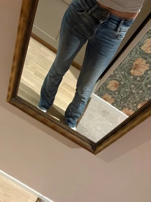 Blå raka jeans med hög midja - Säljer ett par klassiska blå jeans med rak passform och hög midja. Jeansen har fem fickor och stängs med dragkedja och knapp. Perfekta till en avslappnad stil och passar till det mesta i garderoben.