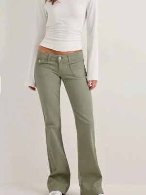 Nelly jeans - Snygga ljusgröna jeans med bootcut passform och låg midja. Jeansen har klassiska fem fickor och vita sömmar som kontrast. Perfekta för en trendig och avslappnad stil. Använda en gång