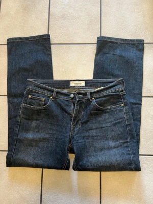 Mörkblå jeans från Dressmann W34 L 32 - Snygga mörkblå jeans från Dressmann med klassisk femficksmodell och raka ben. Jeansen har kontrastsömmar och metallknapp i midjan. Tillverkade i slitstarkt denimtyg som passar perfekt till en avslappnad stil.