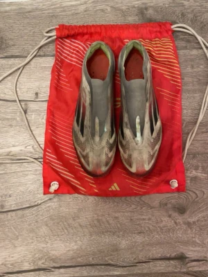 Adidas f50 påse - Säljer ett par Adidas f50 fotbollsskor utan snörning. Skorna är vita med svarta och röda detaljer samt vita sulor. Ovandelen är tillverkad i ett lätt syntetmaterial för maximal fart på planen. Kommer med en röd gympåse med gula detaljer. Skriv gärna vid funderingar😊 priset är inte fast vid snabb affär💸