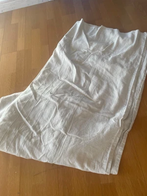 White Linen or Cotton Fabric on Wooden Floor - This image shows a piece of white or off-white fabric, possibly linen or cotton, spread out on a wooden floor. The fabric appears to be wrinkled and is likely a bedsheet, tablecloth, or curtain. The floor is a light brown wood, and the fabric is positioned diagonally across the image.ikea sängövrtkadt 