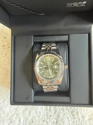 Seiko mod, Sky-Dweller - Stilren klocka från Seiko mod i silverfärg med klassisk länkarmband och räfflad bezel. Urtavlan är mörk med tydliga markeringar och datumvisning. Perfekt accessoar för dig som gillar en tidlös look.