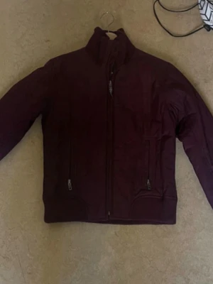 Mörklila vindjacka med dragkedjor - Snygg mörklila vindjacka med hög krage och två praktiska fickor med dragkedja framtill. Jackan har en stilren design och är perfekt för blåsiga dagar. Materialet känns lätt och smidigt, och passformen är klassisk med långa ärmar.