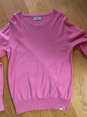 Rosa tröja från Acne Studios - Snygg rosa tröja från Acne Studios i modellen Pop Classics. Tröjan har rund halsringning, långa ärmar och ribbade muddar vid ärmslut och nederkant. Svårt att få bra återgivning av färgen pga ljussättningen i lägenheten. 