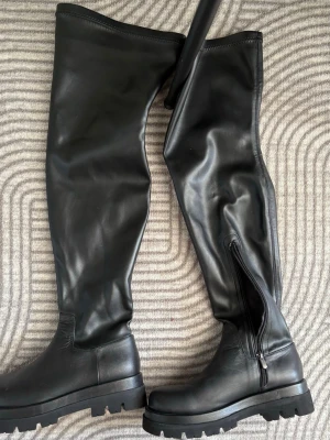 Svarta overknee boots i skinnimitation - Snygga svarta overknee boots med chunky sula och dragkedja på insidan. Tillverkade i skinnimitation med matt finish. Storlek 39🖤