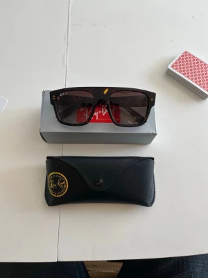 Ray-Ban solglasögon brun - Snygga solglasögon från Ray-Ban med breda, fyrkantiga bågar i mörkbrunt mönster. Glasen är mörka och bågarna har små guldfärgade detaljer vid hörnen. Kommer med original Ray-Ban-fodral i svart skinnimitation.#grisch #2000s #y2k #archive #niche #2016s #fakemink #feng #youngthug #stockholm #ungdom #snygg #marinblå #svart #vit #fin #unik #123 #456 #789 #archivedesigner #timelessdesign #vintage #vinted #fashion #collectorsitem #vintagedesigner #mönster #man #boy #afflction #replay #gats #maisonmargi